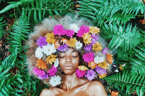 grátis Mulher Com Cocar Floral Deitada Sobre Plantas De Folhas Verdes Foto profissional