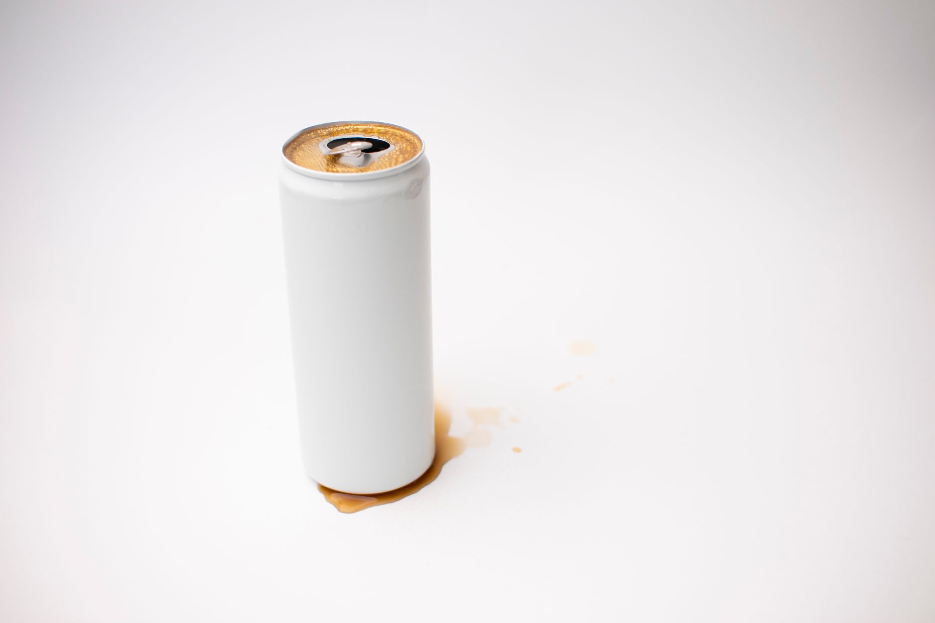 Close-up of a white soda can with spilled liquid on a plain background.