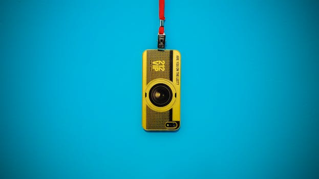 蓝色背景上有一个充满活力的黄色相机钥匙扣与挂绳