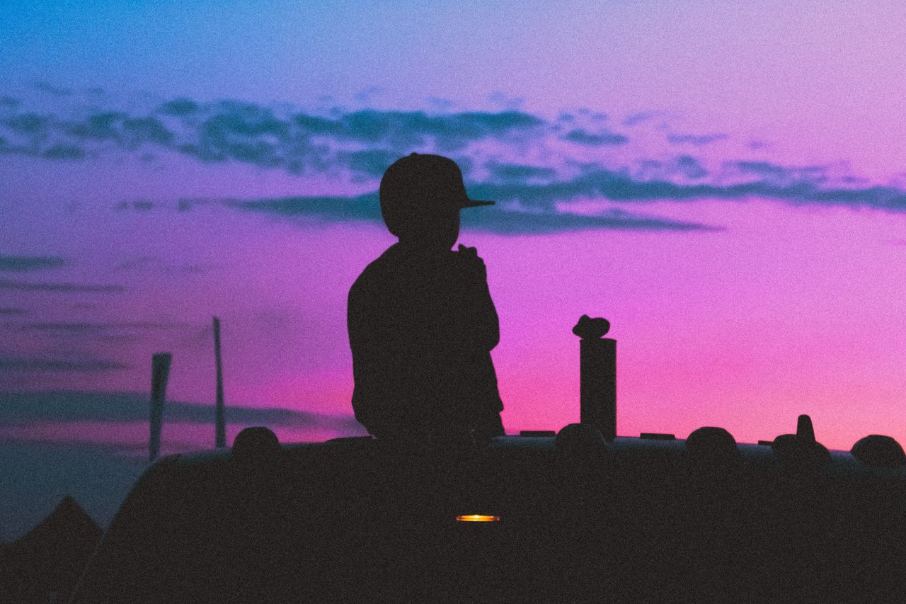silhouette of a child sitting on a vehicle against a vibrant purple su
