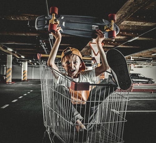 Boy Holding a Penny Board in a Push Cart