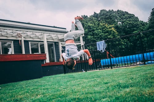 Person in Gray Shirt Doing Trick Under White Clouds and Blue Sky