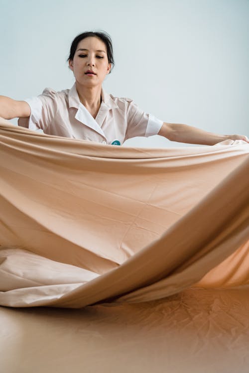 Woman Putting Bedsheet in a Bed