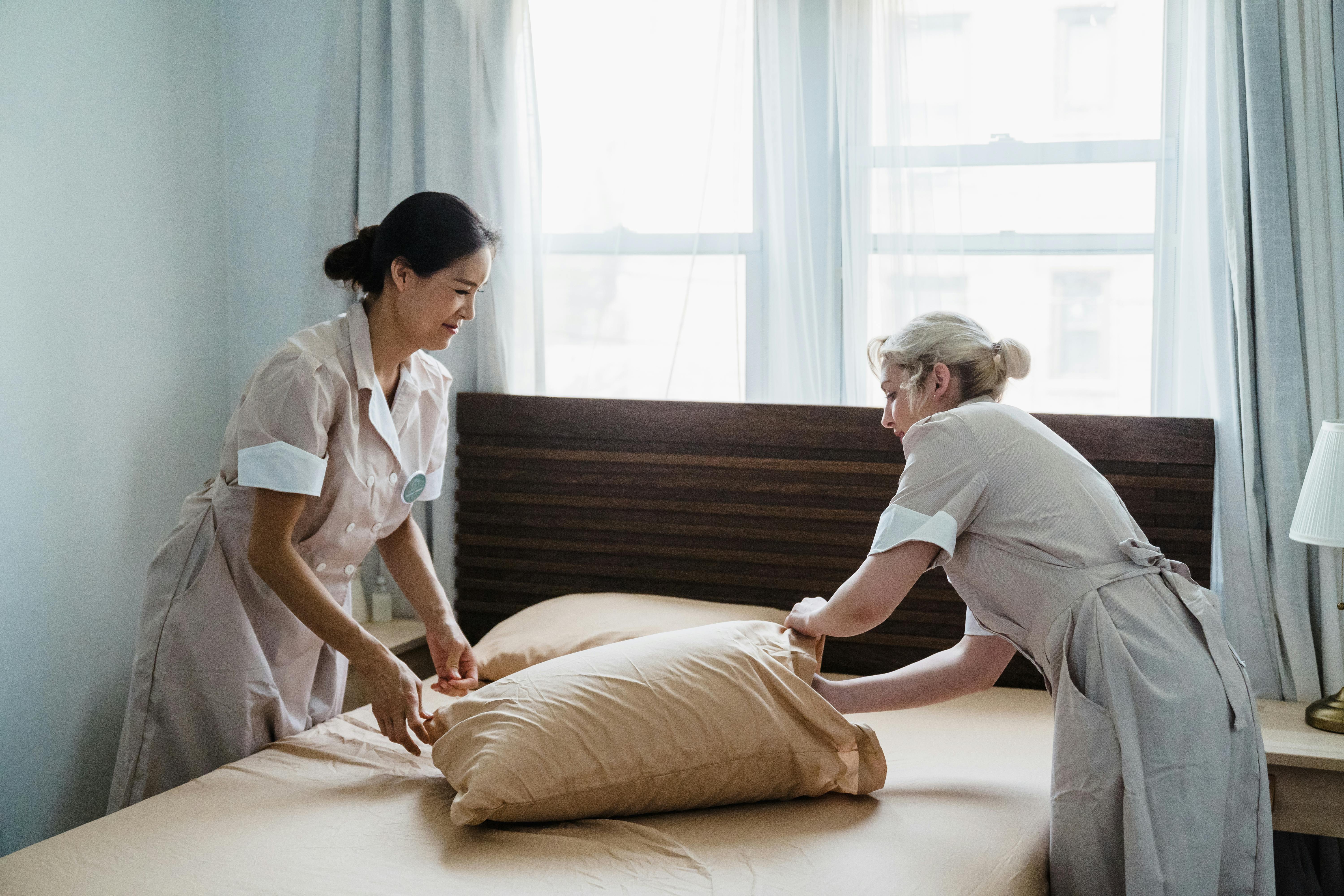 a woman putting a pillow on a pillowcase