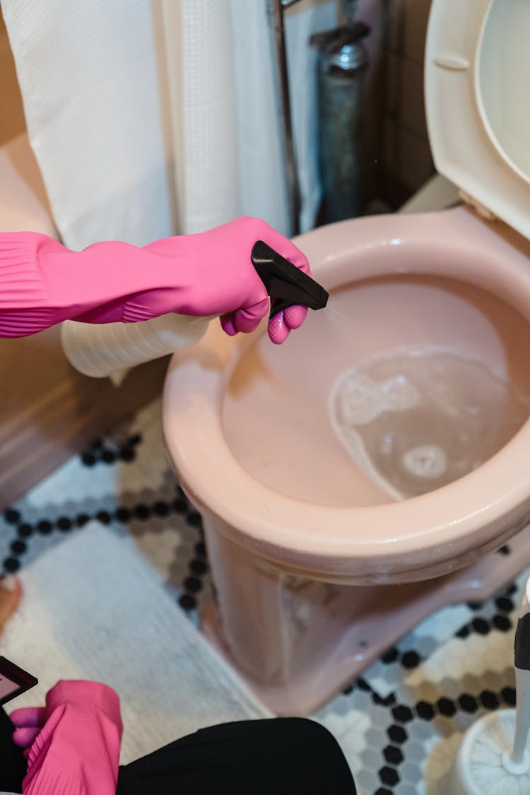 Spraying Liquid Cleaner In The Toilet