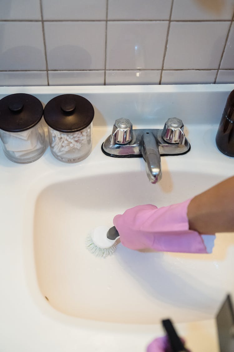 A Person Cleaning A Sink