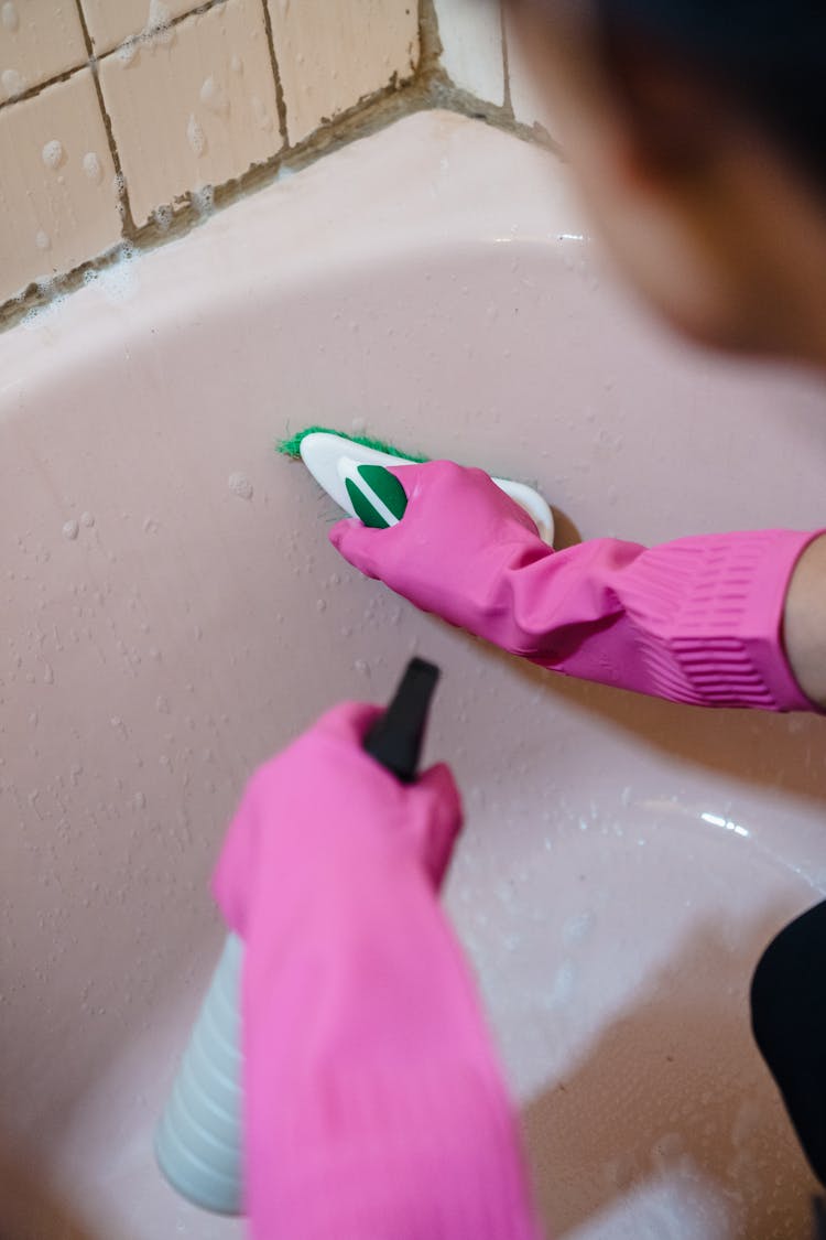 Woman In Pink Gloves Cleaning Bathtub