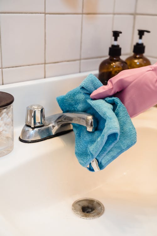Free Person Wiping  A Stainless Steel Faucet With Blue Towel Stock Photo