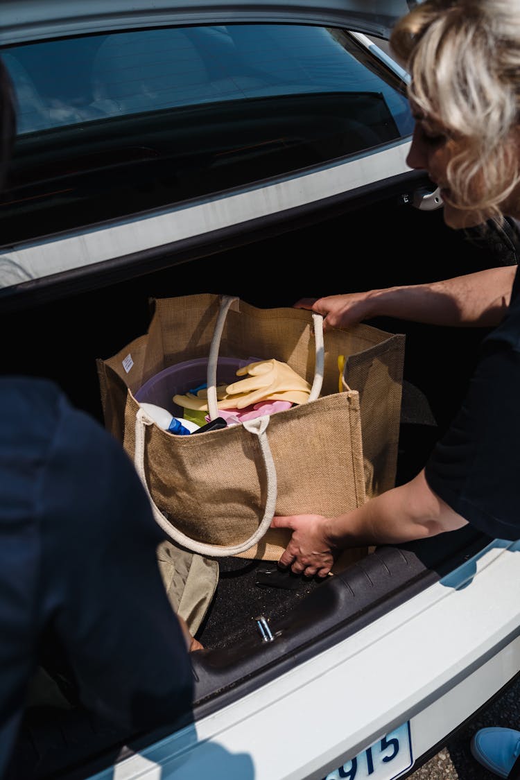 A Woman Putting A Bag In The Car Trunk