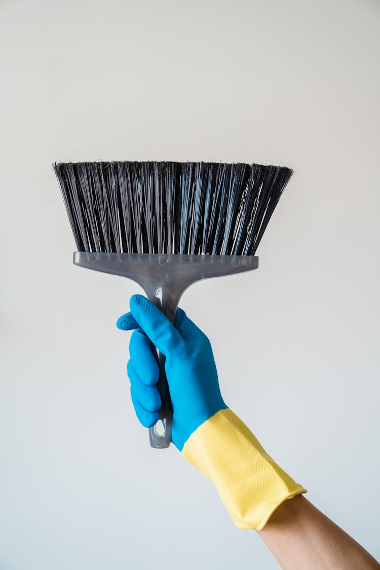 Hand In Blue Glove Holding Broom