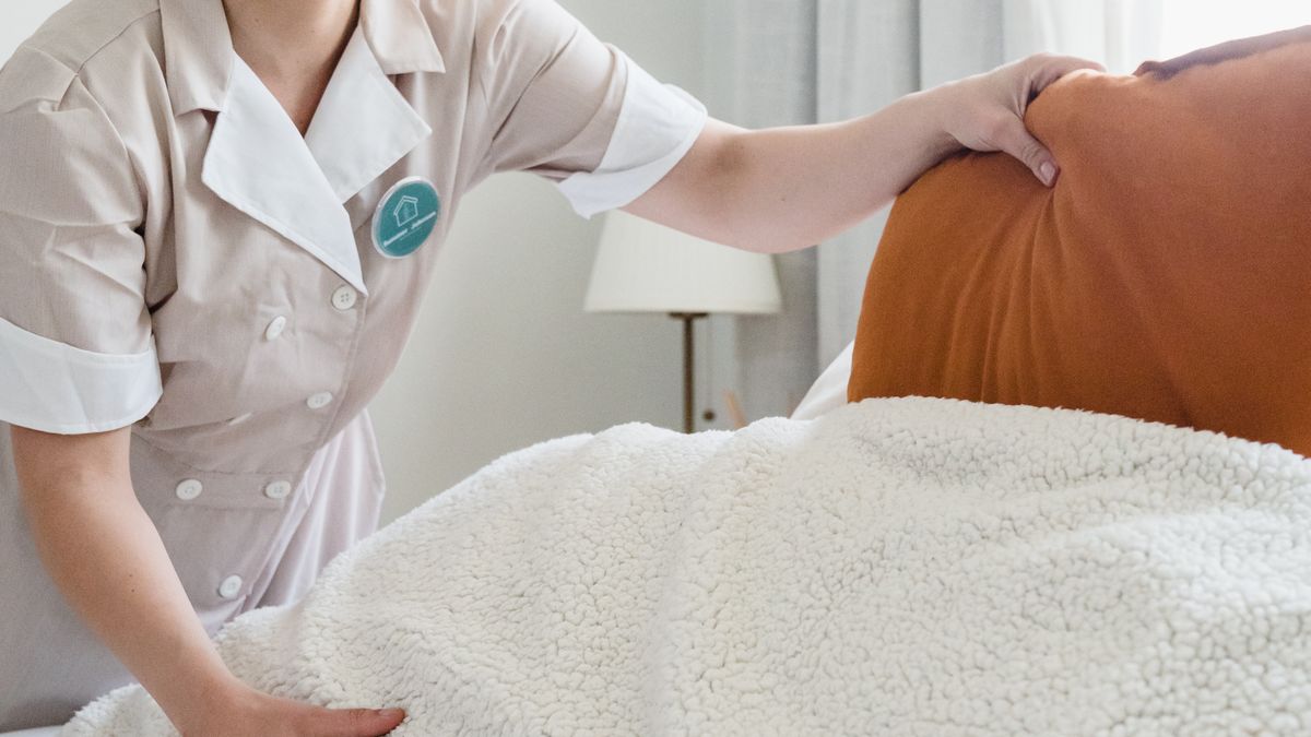A housekeeper making up a hotel bed with fresh white linens