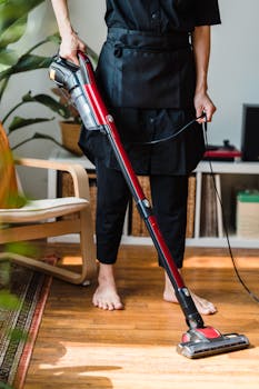 A person vacuuming a wooden floor in a cozy living room setting indoors