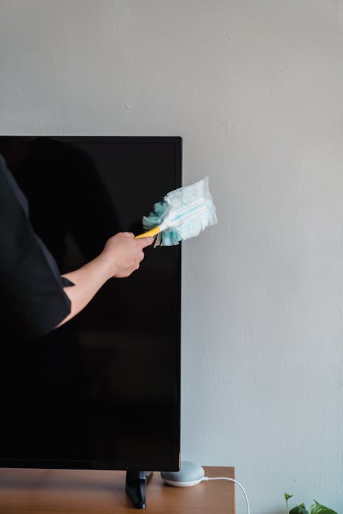 A Person Dusting a TV Set