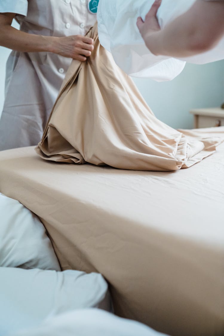 Close-up Of Housekeepers Changing Bedding In Hotel