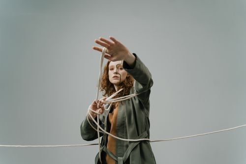Free Portrait of a woman with auburn hair holding a rope in a studio setting with a gray background. Stock Photo