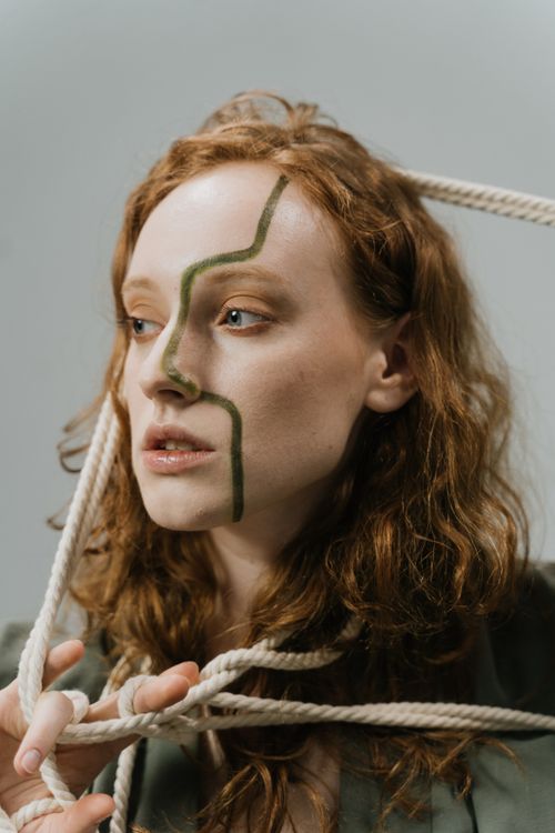 Free Creative portrait of a woman with face paint and tangled ropes, evoking intrigue. Stock Photo