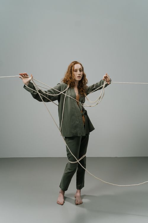 Free Artistic studio shot of a woman in green attire holding ropes, conveying a sense of entanglement and creativity. Stock Photo