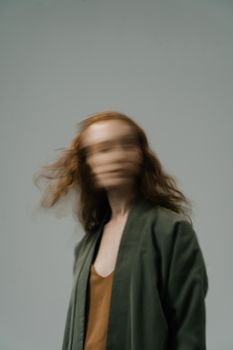 Blurred artistic portrait of a redhead woman in motion, conveying dynamic movement and fashion style.