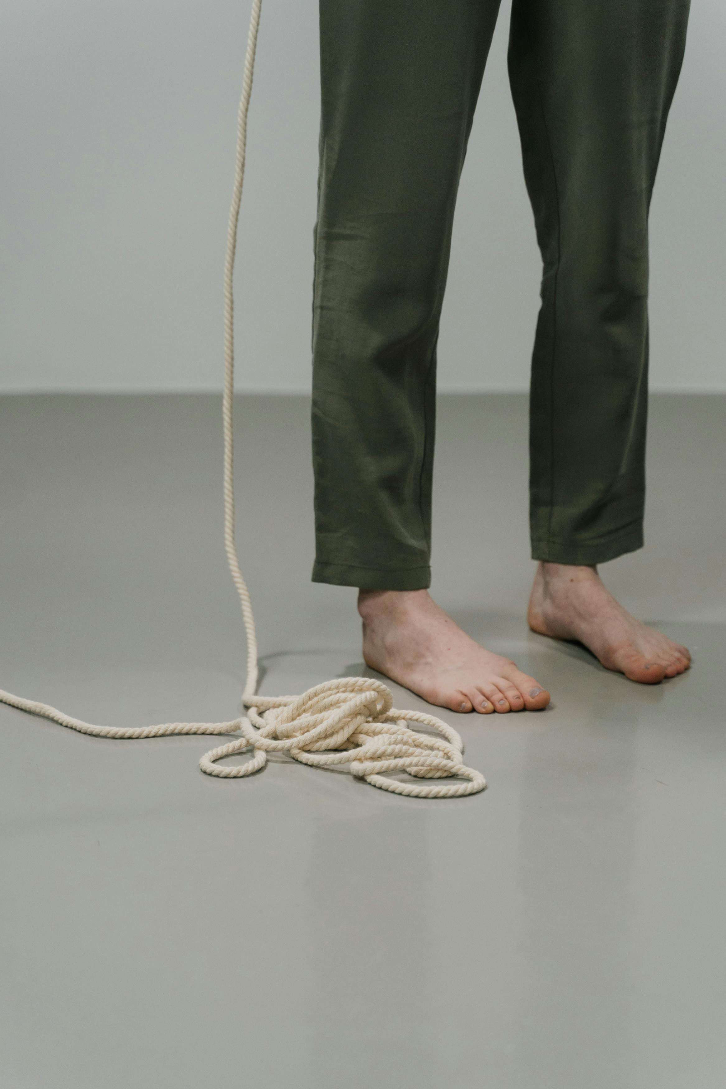 person standing barefoot of the floor next to a rope