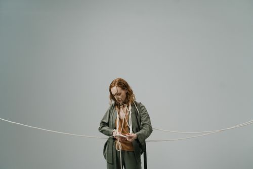 Free Redheaded woman looking down while entangled in rope during a minimalist studio shoot. Stock Photo