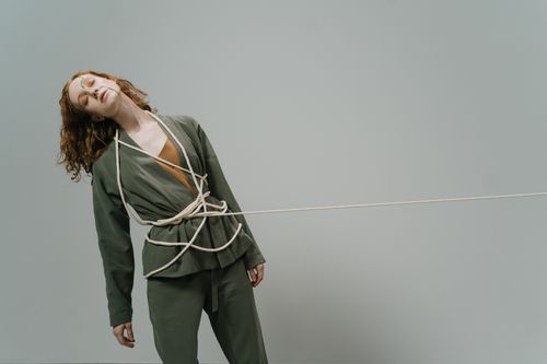 Free A studio shot of a woman wrapped in rope against a gray background, evoking conceptual themes. Stock Photo