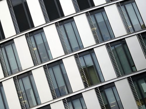 Free Angled view of a modern office building with large glass windows and steel accents. Stock Photo