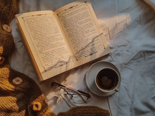 Free Relax with a warm cup of coffee, a classic book, and a knit cardigan in a comfy setting. Stock Photo
