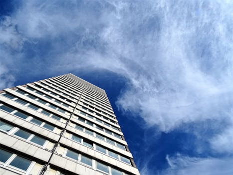 从下方仰望，高耸的摩天大楼与流动的云层、充满活力的蓝天相映成趣