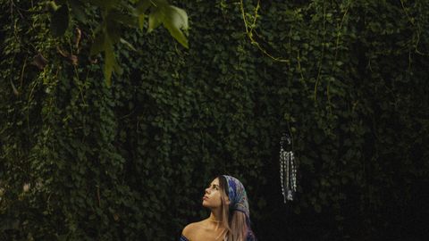 A woman sits in meditation amidst lush greenery, embodying peace and mindfulness in nature.