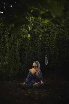 A woman sits in meditation amidst lush greenery, embodying peace and mindfulness in nature.