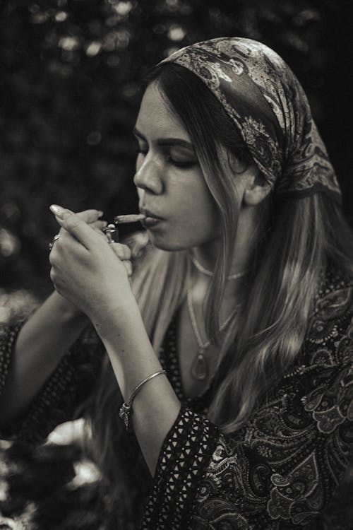 Grayscale Photo of a Woman Lighting a Joint