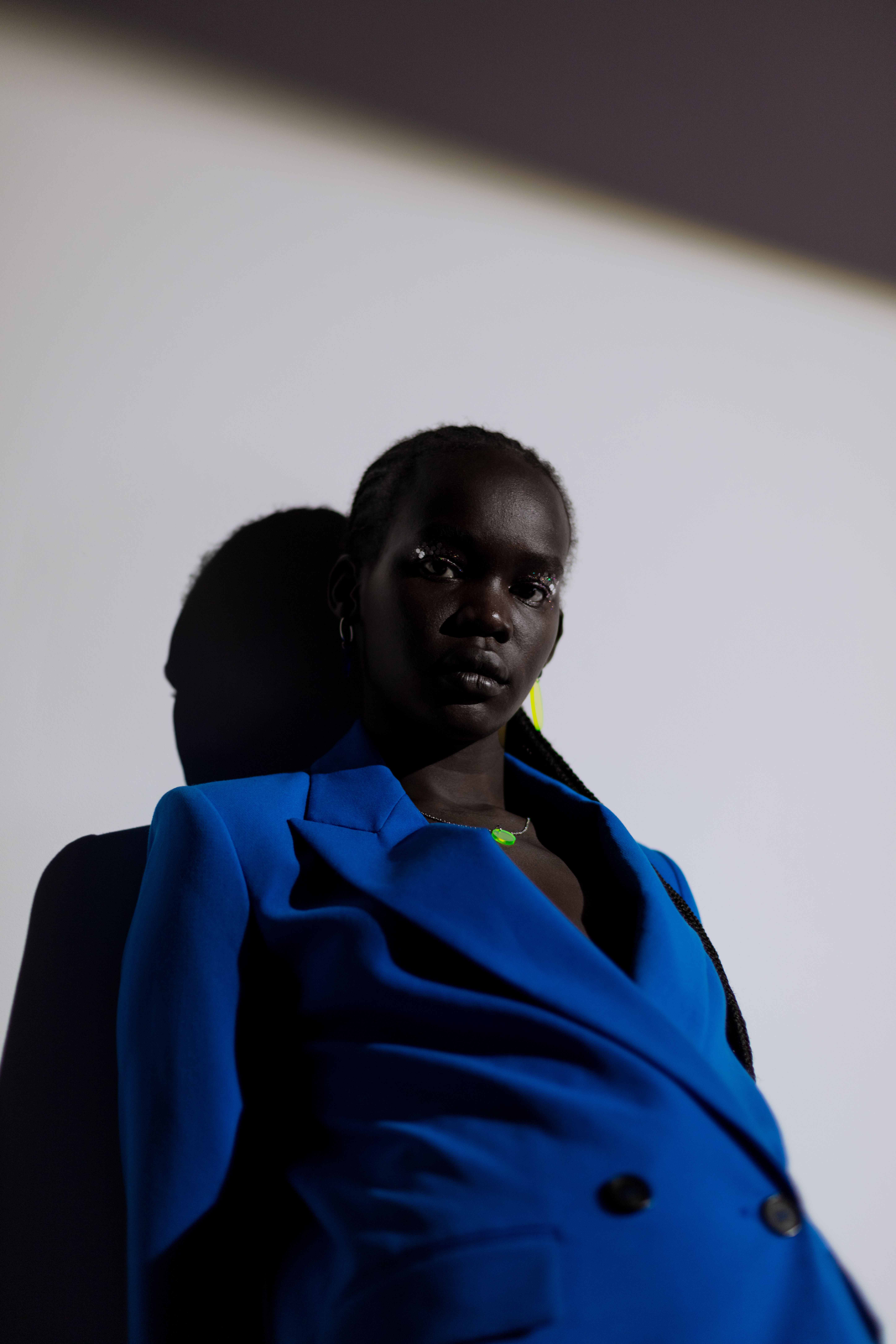 African American woman striking a pose in a studio wearing a blue suit jacket against a neutral background.
