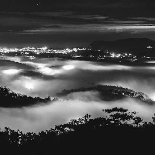 Grayscale Photo of Hills Covered with Thick Fog 