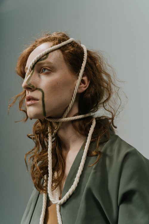 Free Artistic side view portrait of a woman with ginger hair and ropes, symbolizing stress. Stock Photo