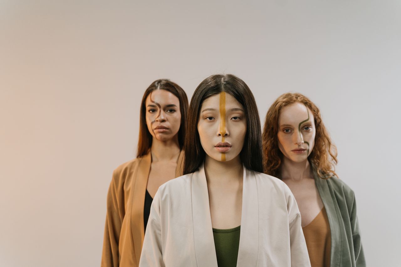a diverse group of women with face paint poses confidently in a studio