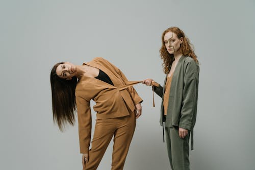 A Woman Holding another Woman's Belt while Posing Together