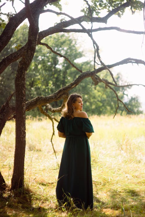 Free Woman in Green Off Shoulder Dress Standing Beside A Brown Tree Stock Photo