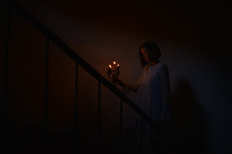 Woman Walking Up Stairs Holding Lit Candles