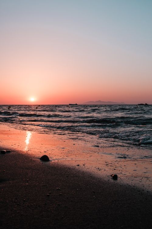 Free Experience a tranquil beach sunset with vibrant colors reflecting on the gentle waves. Stock Photo
