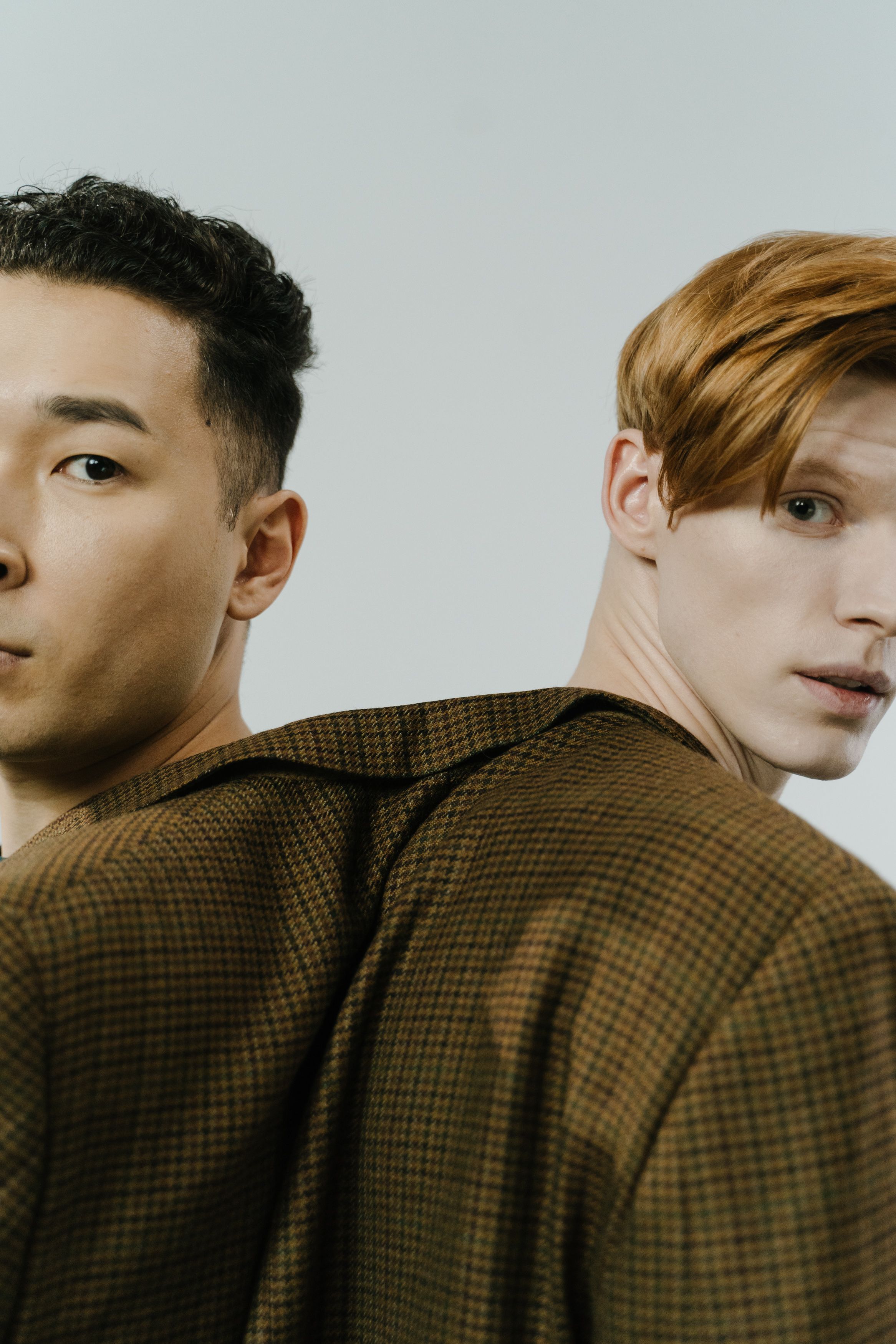 Close-up portrait of two men in brown coats showing diversity and fashion.