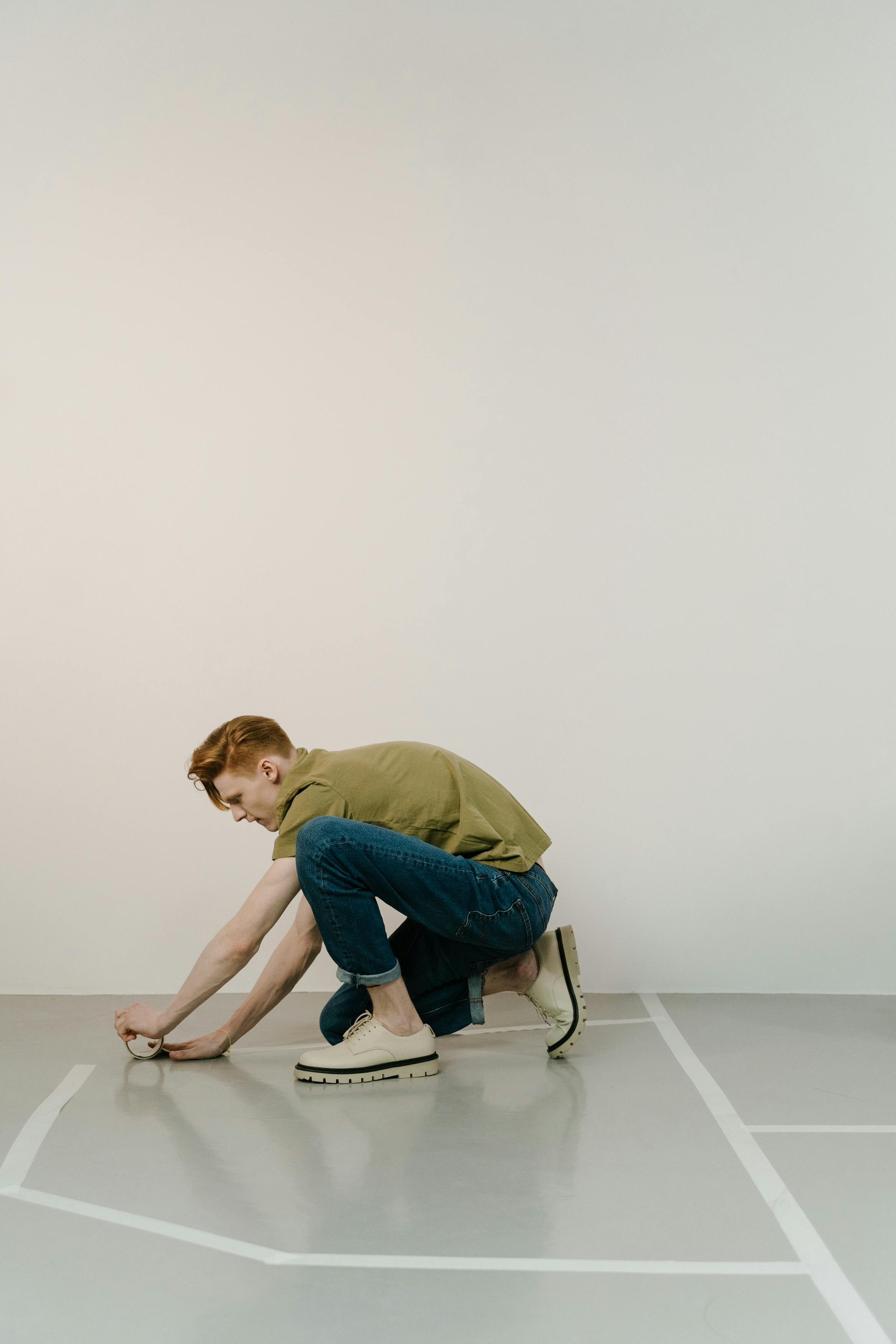 man sticking tape to the floor