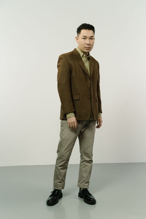 Free Man wearing brown blazer and khaki pants posing in studio setting, elegant fashion. Stock Photo