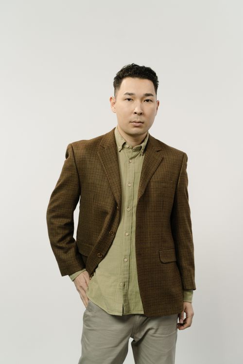 Free A stylish man wearing a brown blazer poses confidently in a studio setting. Perfect for fashion concepts. Stock Photo