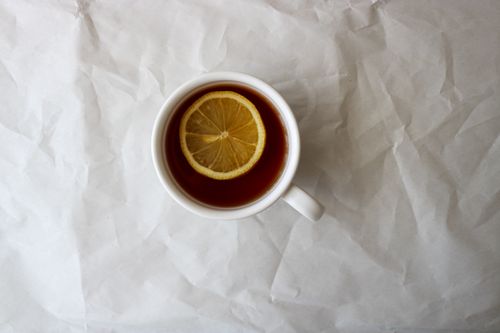 Free Overhead shot of a white cup of tea with a lemon slice on a wrinkled paper surface. Stock Photo
