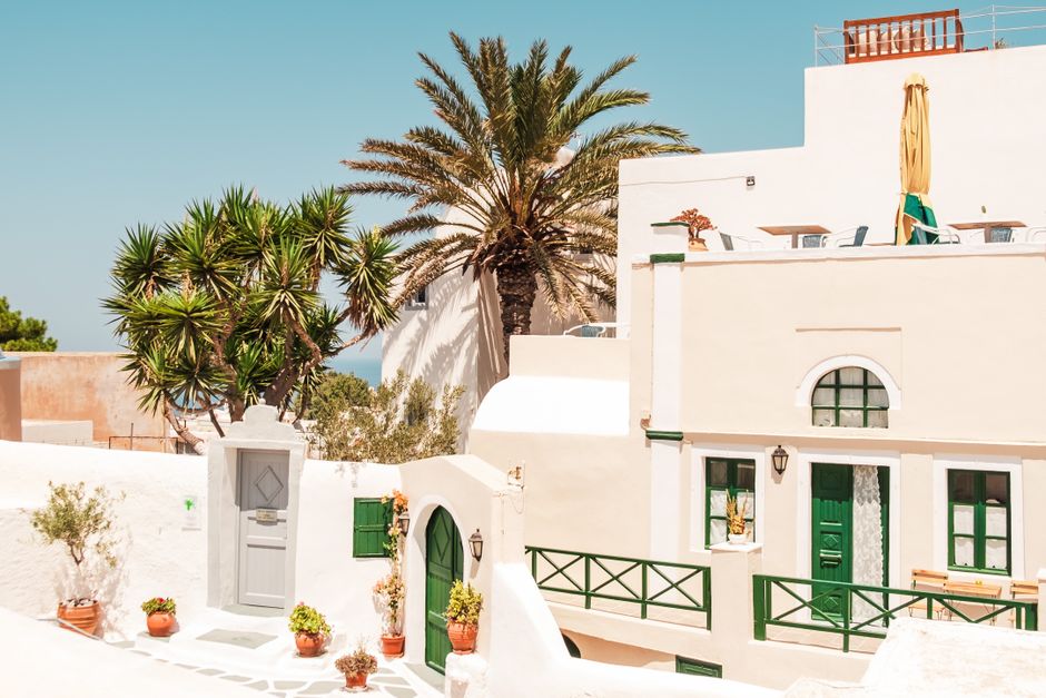 Whitewashed Mediterranean house with balcony, terrace and palm trees under a clear sky