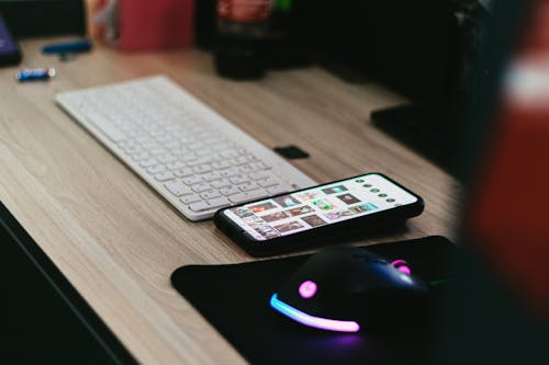 Photo of a Cell Phone Near a Mouse and Keyboard