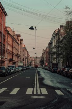 Charming urban street at dusk with historic architecture and parked cars lining the way.