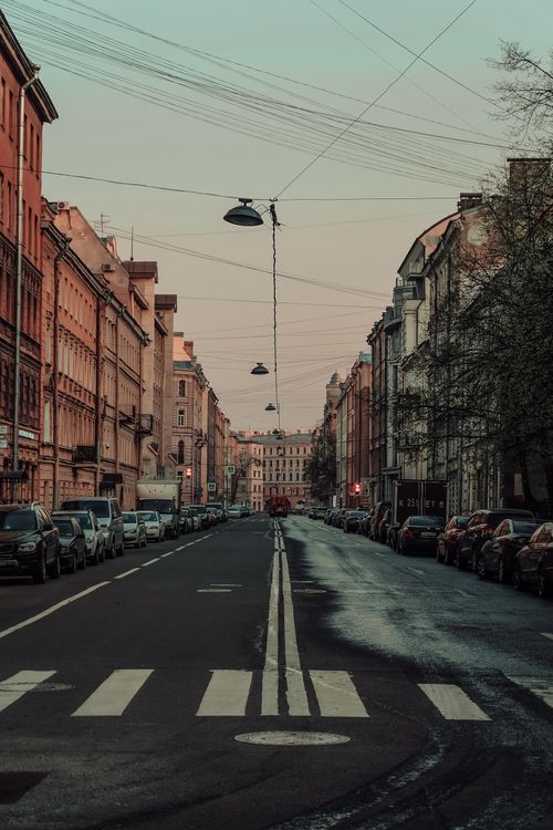 Free Charming urban street at dusk with historic architecture and parked cars lining the way. Stock Photo