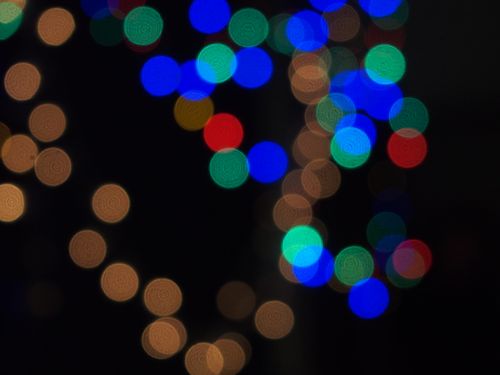 Free Abstract black background with glowing differently colored bokeh spots creating impression of defocused fairy lights at late night home party Stock Photo