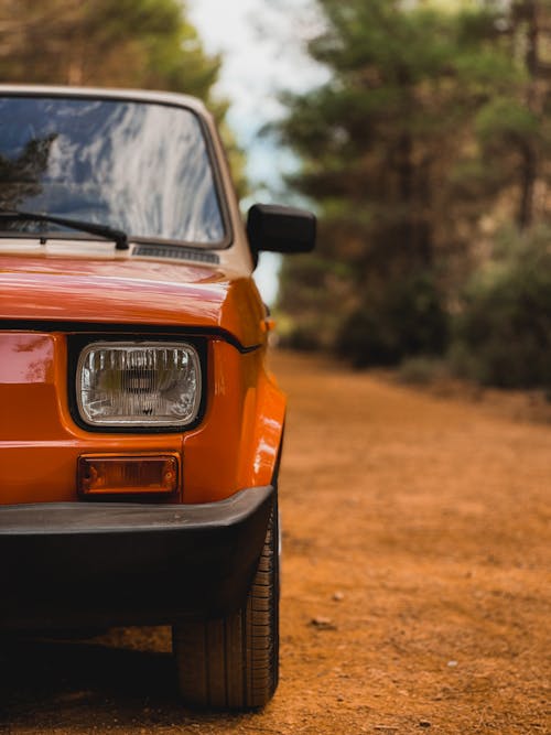 Parked Orange Car on Unpaved Road